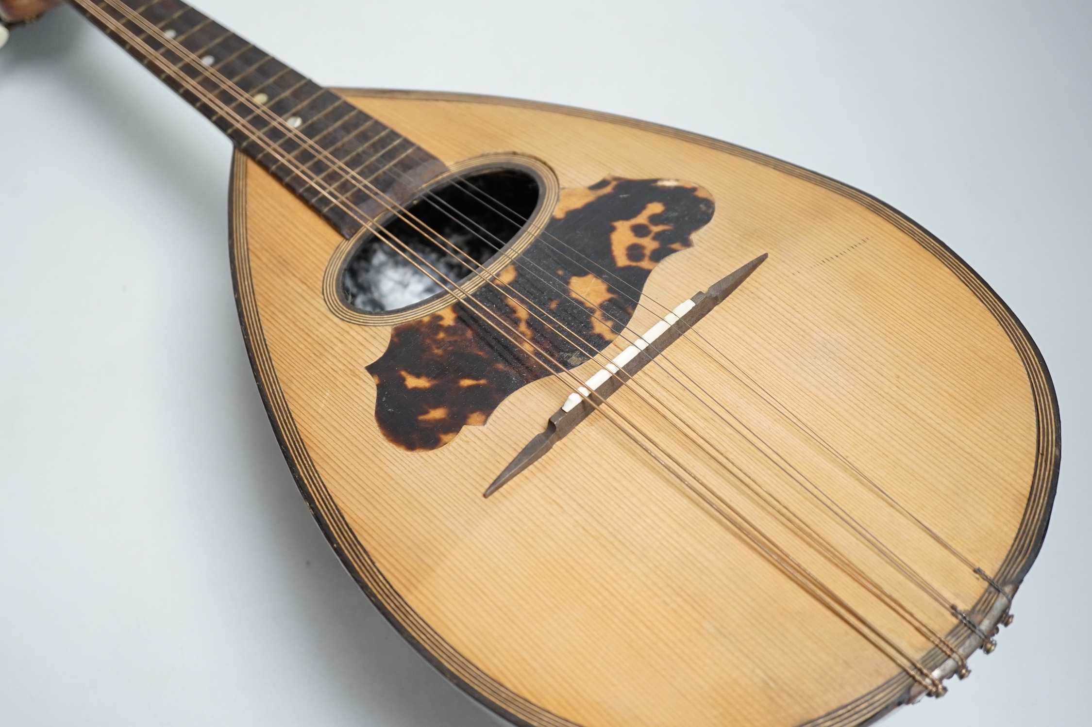 A cased mandolin with tortoiseshell detail, bone tuning pegs, 61cm long
